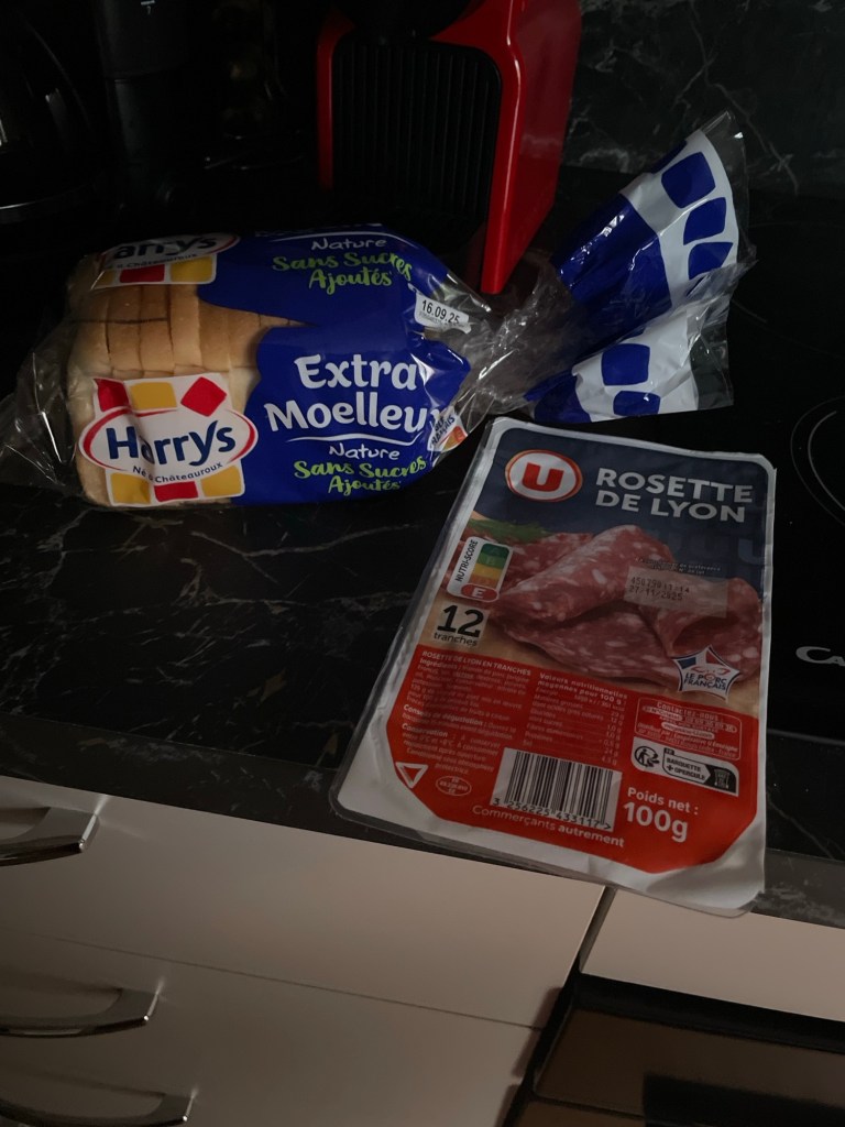 Kitchen counter with a plastic-bagged loaf of sliced white bread (reminiscent of Wonder Bread, but French) and a package of rosette de Lyon sliced hard salami. 