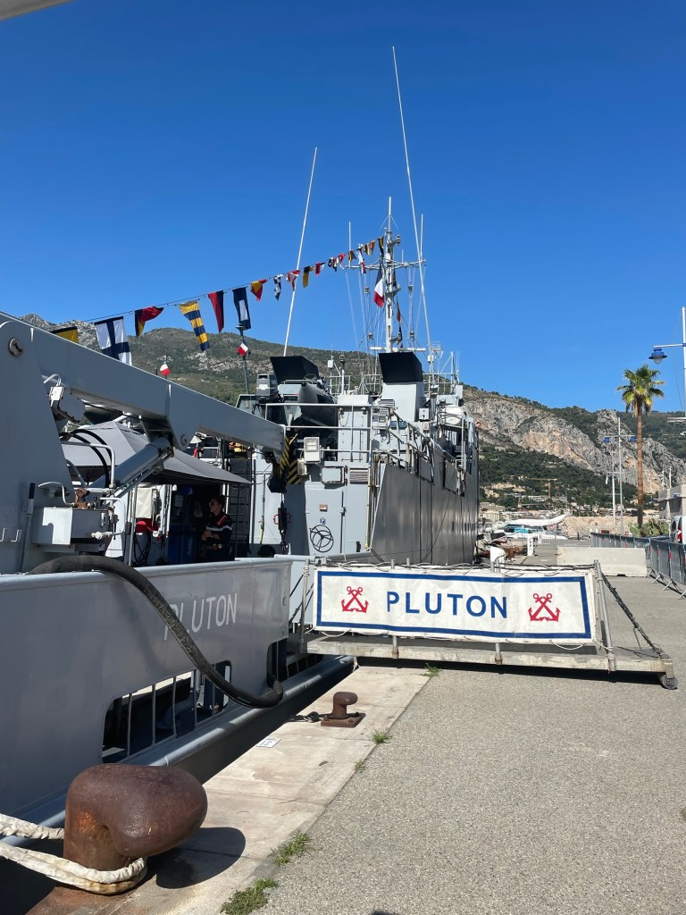 Naval vessel in dock:  Le Pluton.  Colorful flags fly from it